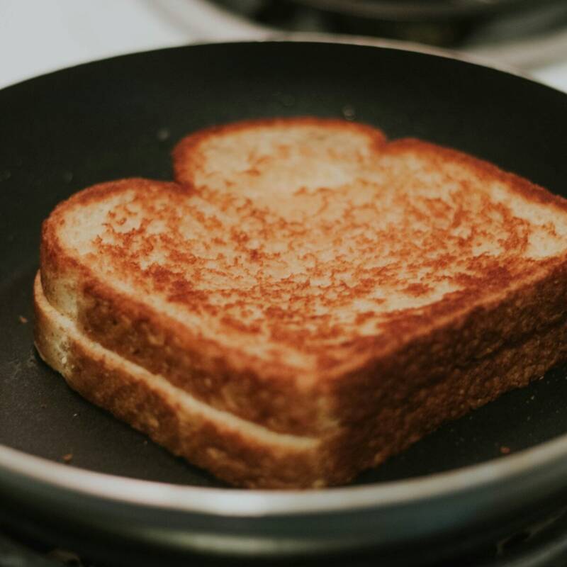 Classic grilled cheese sandwich melting in a skillet on the stove