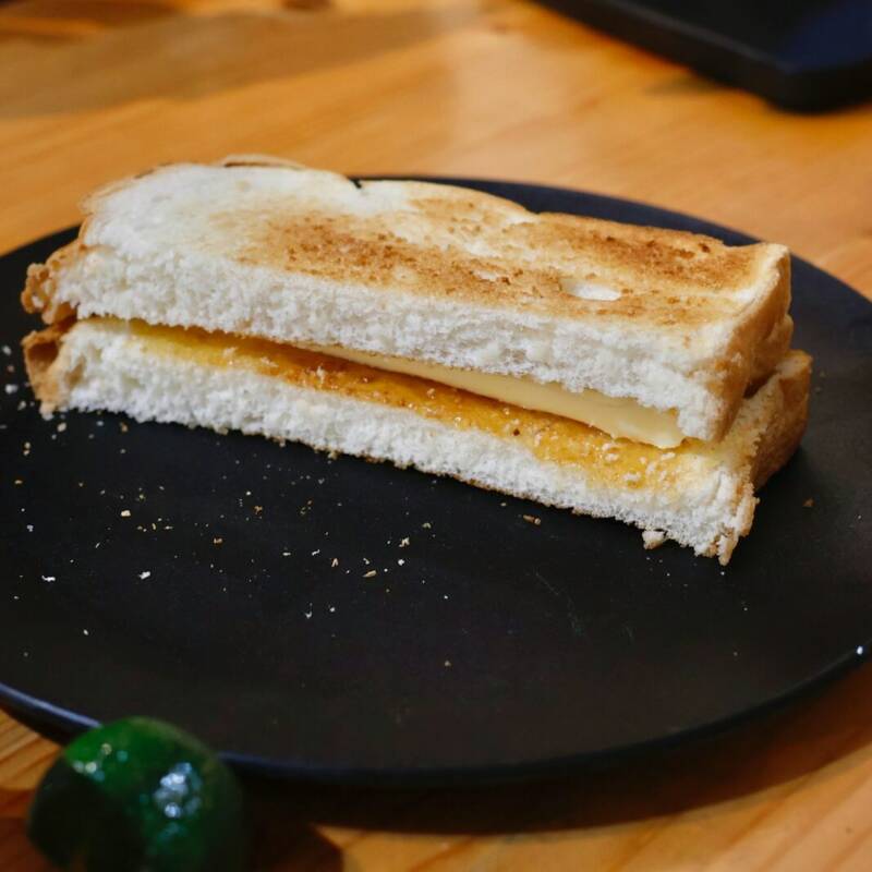 Toasted classic grilled cheese sandwich sliced in half on a black plate