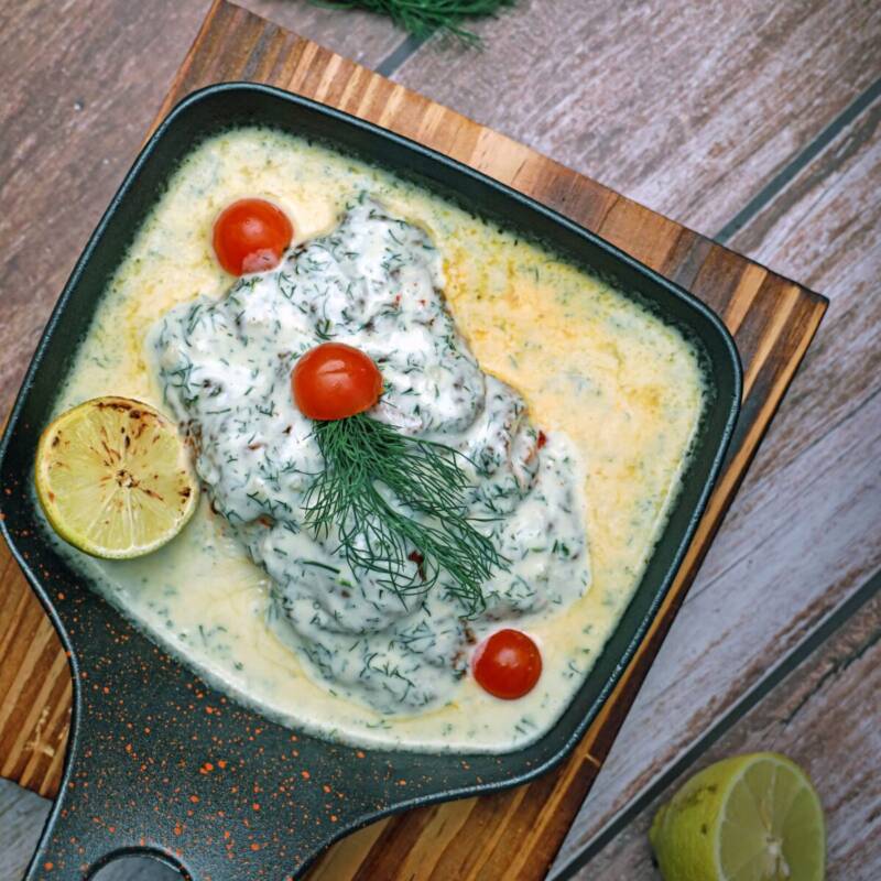 Pan seared lemon garlic butter salmon with vegetables on wooden board