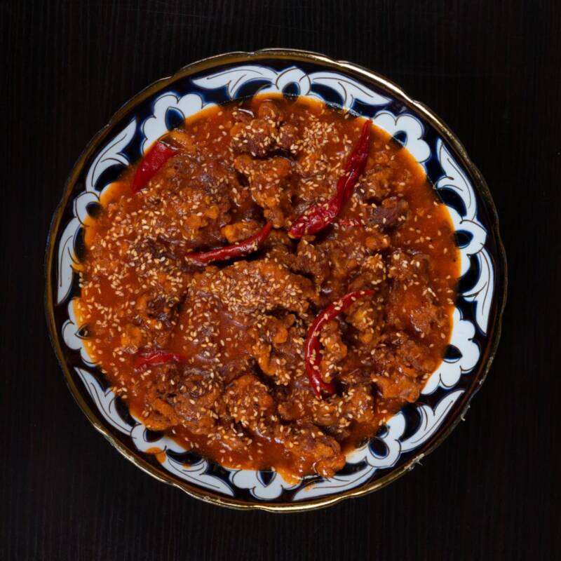 Bowl of beef chili topped with red peppers