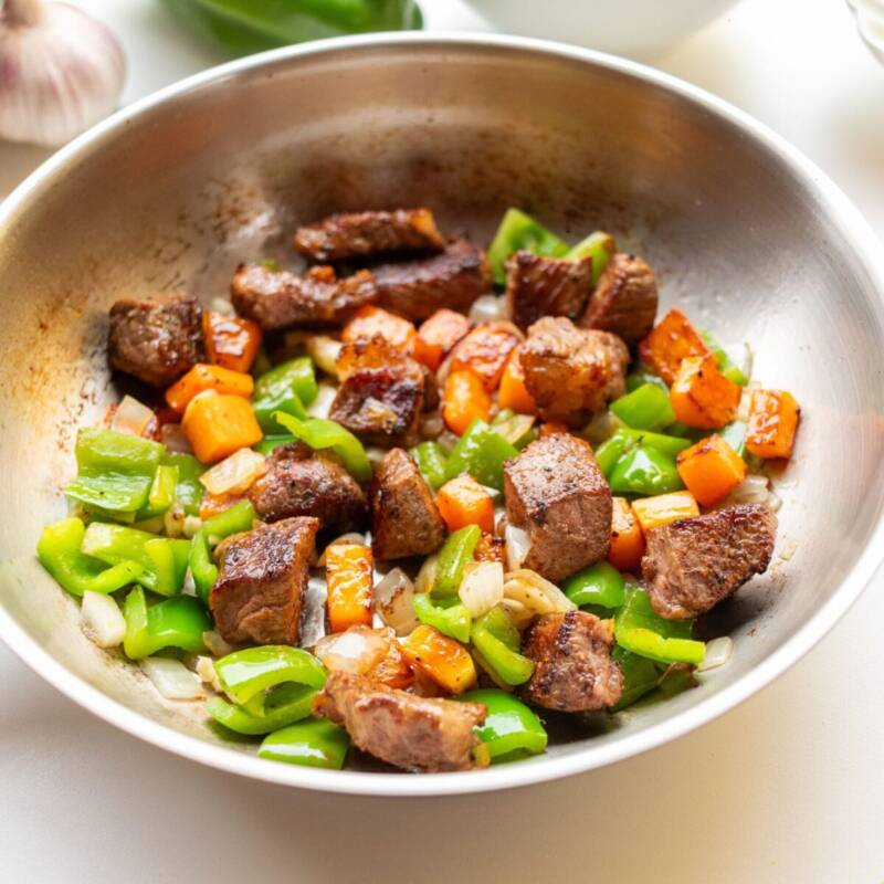 Beef and broccoli stir fry sizzling with bell peppers and carrots in a hot pan