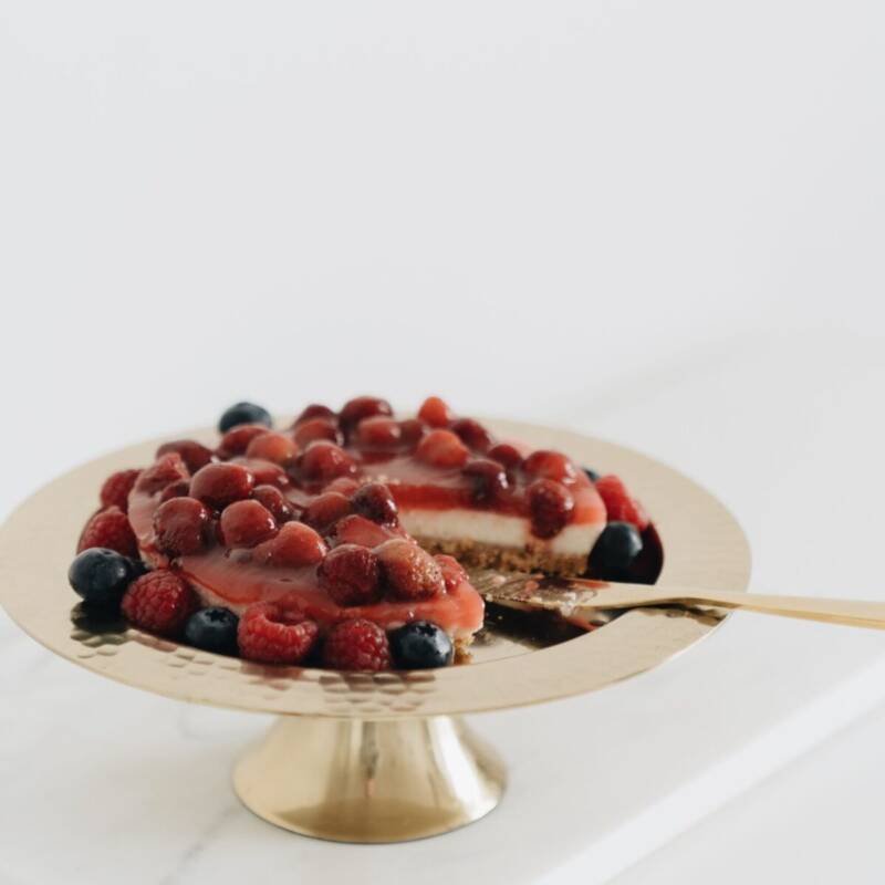 Overhead view of a whole no bake cheesecake topped with mixed berries on a cake stand