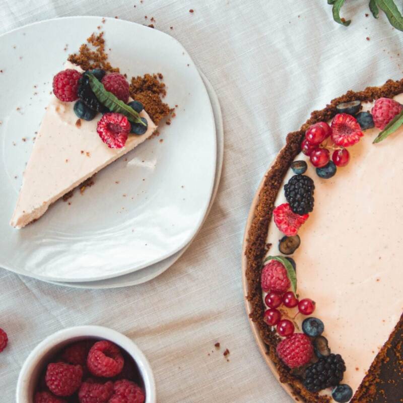 No bake cheesecake with a graham cracker crust and a clean sliced edge on a white plate