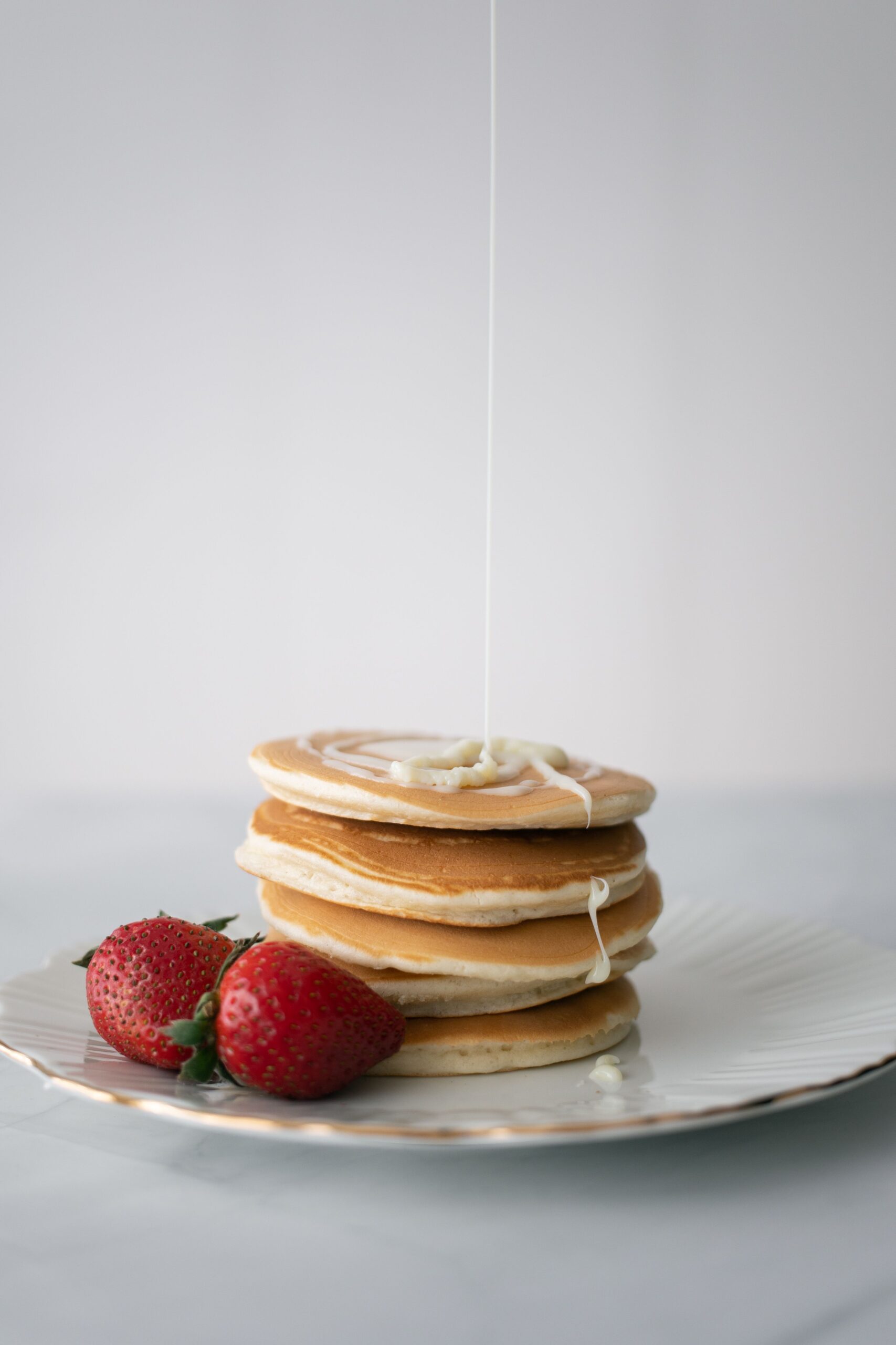 Berries and syrup drizzled over a stack of fluffy buttermilk pancakes