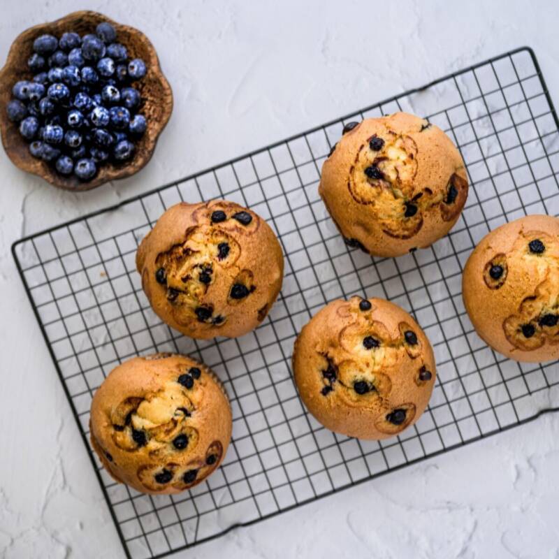 Best blueberry muffins with golden domed tops cooling on a wire rack